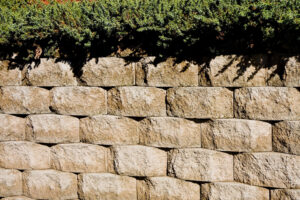 A stone block retaining wall topped with hedge